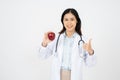 Female doctor with a white coat smiling and holding an apple Royalty Free Stock Photo