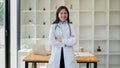 female doctor in a white coat with a stethoscope looking at the camera, smiling. posing in the hospital office with arms Royalty Free Stock Photo