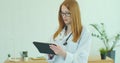 Female doctor in white coat using modern TabletPC device with touch screen. Doctor using DigitalTablet texting to Royalty Free Stock Photo