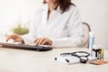 Female doctor in white lab coat,hands typing on laptop computer keyboard with medical stethoscope and  medicine on the mirror desk Royalty Free Stock Photo