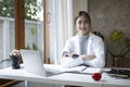 Female doctor in white medical uniform sitting at office desk and smiling at camera. Royalty Free Stock Photo