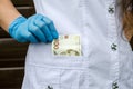 Female doctor in white puts the hryvnias in his pocket. Close-up. A  hand in a glove takes money from his pocket. Royalty Free Stock Photo