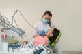 The female doctor in white uniform treats the teeth with caries of a young woman with a drill Royalty Free Stock Photo