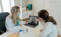 Happy female doctor and patient wearing protective face mask having a consultation in clinic office Royalty Free Stock Photo