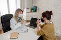 Happy female doctor and patient wearing protective face mask having a consultation in clinic office Royalty Free Stock Photo