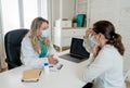 Happy female doctor and patient wearing protective face mask having a consultation in clinic office Royalty Free Stock Photo