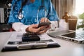 Female doctor working on desk with smartphone and laptop computer and paperwork in the office. Royalty Free Stock Photo