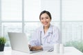 Female doctor working with laptop at office desk and smiling Royalty Free Stock Photo