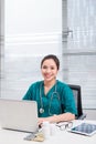 Female doctor working at office desk and smiling at camera, office interior Royalty Free Stock Photo