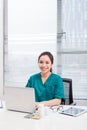 Female doctor working at office desk and smiling at camera, office interior Royalty Free Stock Photo