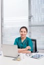 Female doctor working at office desk and smiling at camera, office interior Royalty Free Stock Photo
