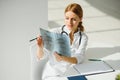 Female doctor working at office desk and smiling, office interior on background. Royalty Free Stock Photo