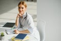 Female doctor working at office desk and smiling, office interior on background Royalty Free Stock Photo