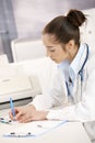 Female doctor writing at desk Royalty Free Stock Photo