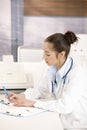 Female doctor writing at desk Royalty Free Stock Photo