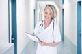 Female doctor writing notes in hospital corridor Royalty Free Stock Photo