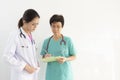 Female doctors consulting in bright office, discussing document