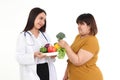 Female doctors, nutritionists carrying fruit and vegetables, advise women who are overweight.