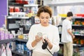 Female dog owner with dog lead leash in her hands carefully examines cans of wet dog food