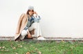 Female dressed fashion multilayered autumn outfit posing at camera near the white wall