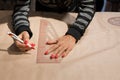 Female dressmaker hands tailor mark drawing on craft paper for making patterns