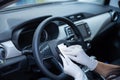 Female driver disinfecting the phone with a rag near the steering wheel