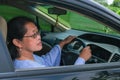 female driver looking at car side mirror from her seat behind the steering wheel to make a right turn