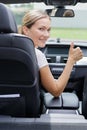 female driver turning to back and making thumbs up gesture