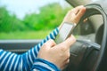 Female driving car and texting sms message on smartphone