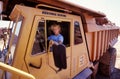 Female dump truck driver sitting in the cab of her huge ore carrying truck