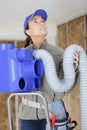 Female elctrician fitting air conditions pipe in building ceiling Royalty Free Stock Photo