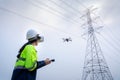 A female electrical engineer flying drone survey area of high voltage pylon with vr goggles at high voltage power plant pylon to