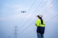 A female electrical engineer flying drone surveying area of high voltage pylons with wearing vr goggles in aerial view to inspect