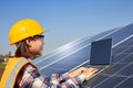 A female electrical engineer is using a laptop to control the operation of the solar panel