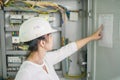 A female electrician checks the electrical box. A girl in an engineering helmet is on the background of a fuse box. Portrait of an