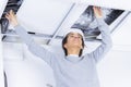 Female electrician installing lights in ceiling