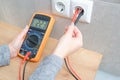 female electrician measures the voltage in the home network. Close-up view of the hands with the appliance near the socket