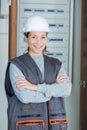 female electrician standing in front open fuse box