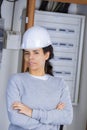 Female electrician standing in front open fuse box