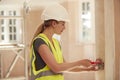 Female Electrician Wearing Hard Hat Fitting Light Switch At New Build Property Royalty Free Stock Photo