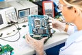 Female electronic engineer examining computer motherboard in lab Royalty Free Stock Photo