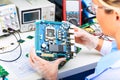 Female electronic engineer examining computer motherboard in lab