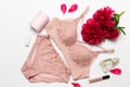 Female elegant pink lace bra, flat peony, lipstick, hand cream and barrette on a white background, flat lay