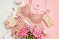 Female elegant pink lace bra and panties, pink candles, hair tie, a bouquet of beautiful peonies, nail polish, jewelry, top view Royalty Free Stock Photo