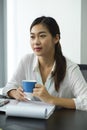 Female employee holding a coffee cup while sitting in a meeting room Royalty Free Stock Photo