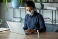 Female employee in face mask disinfect computer at workplace