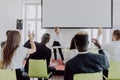 Female employee raise hand asking question to businesswoman making flipchart presentation. Young woman answering during Royalty Free Stock Photo