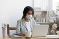 Female employee in medical mask working in office