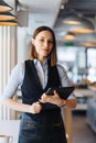 Female employer holding digital tablet while looking forward to meeting with partners