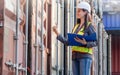 Female engineer with clipboard inspecting cargo containers, Foreman worker checking containers box at shipping container yard Royalty Free Stock Photo